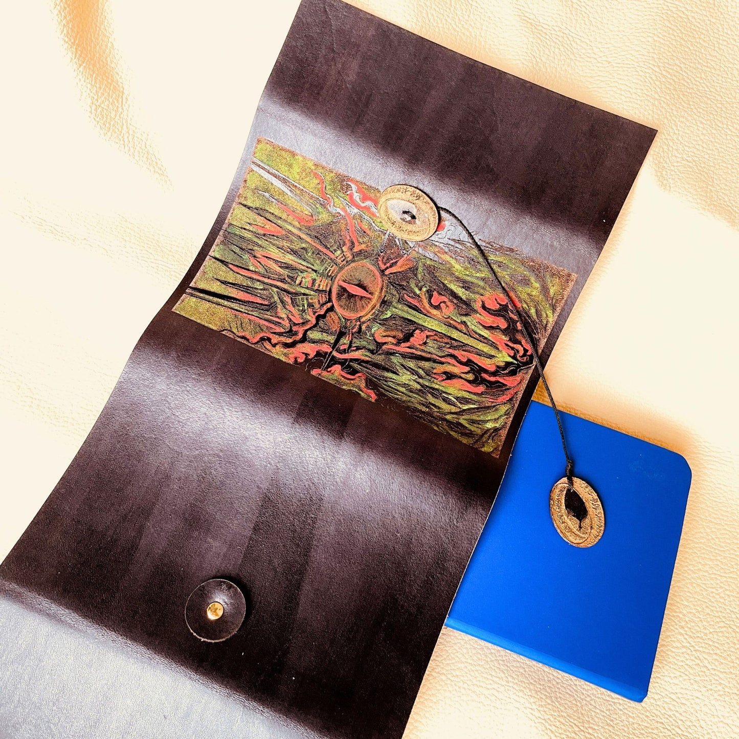 SteamVoyage - copertina in cuoio tinto di nero per agenda A6 con incisione a laser della Torre di Sauron dipinta a mano con colori fluo e cordino per la chiusura ornato da due anelli del potere in cuoio dorato