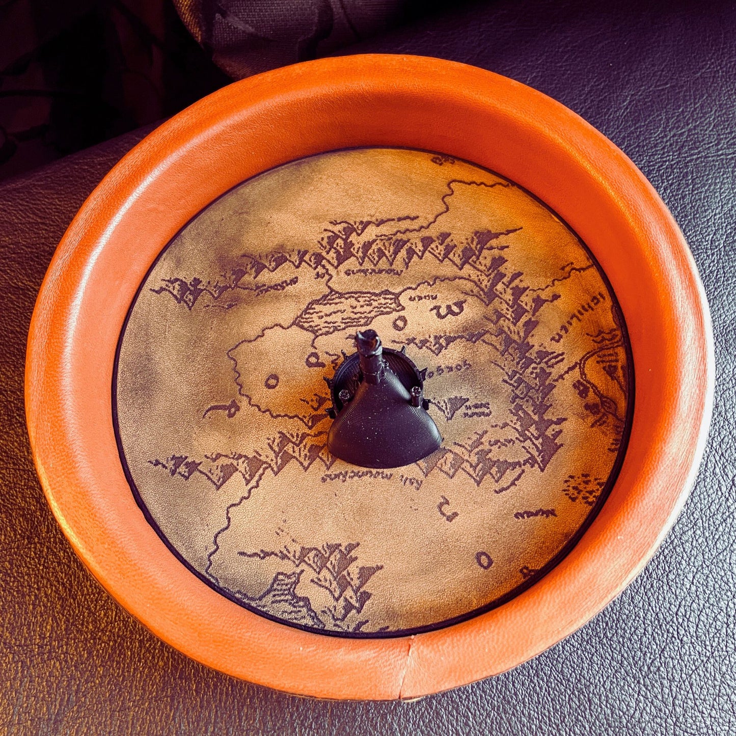 SteamVoyage - vassoio lancia dadi Torre di Sauron in cuoio e legno con incisione a laser della Mappa della Terra di Mezzo e Torre di Sauron in 3d; sul bordo del vassoio lancia dadi è presente l'incisione in elfico sull'Anello del Potere e il fondo nasconde una power bank in grado di illuminare la scritta dell'anello grazie ad un telecomando