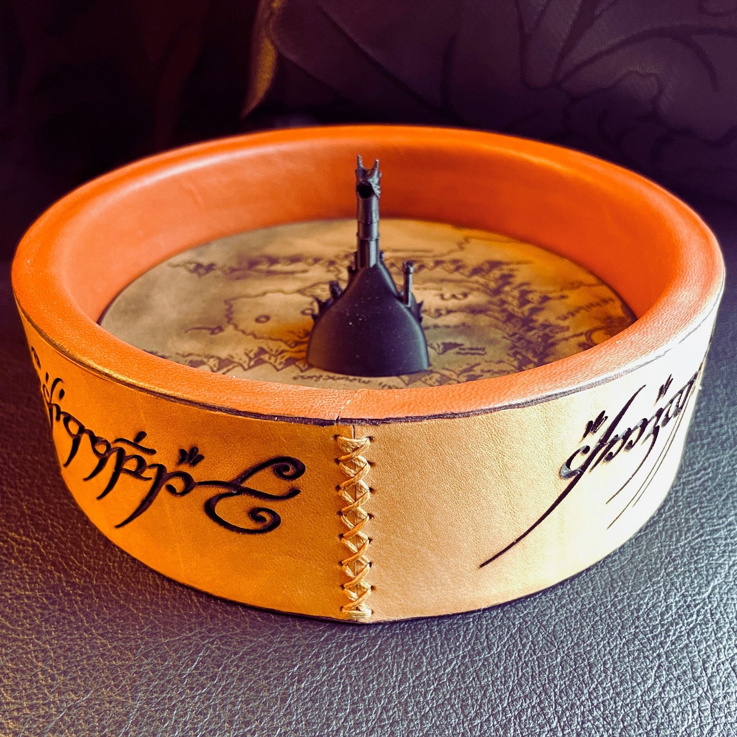 SteamVoyage - vassoio lancia dadi Torre di Sauron in cuoio e legno con incisione a laser della Mappa della Terra di Mezzo e Torre di Sauron in 3d; sul bordo del vassoio lancia dadi è presente l'incisione in elfico sull'Anello del Potere e il fondo nasconde una power bank in grado di illuminare la scritta dell'anello grazie ad un telecomando