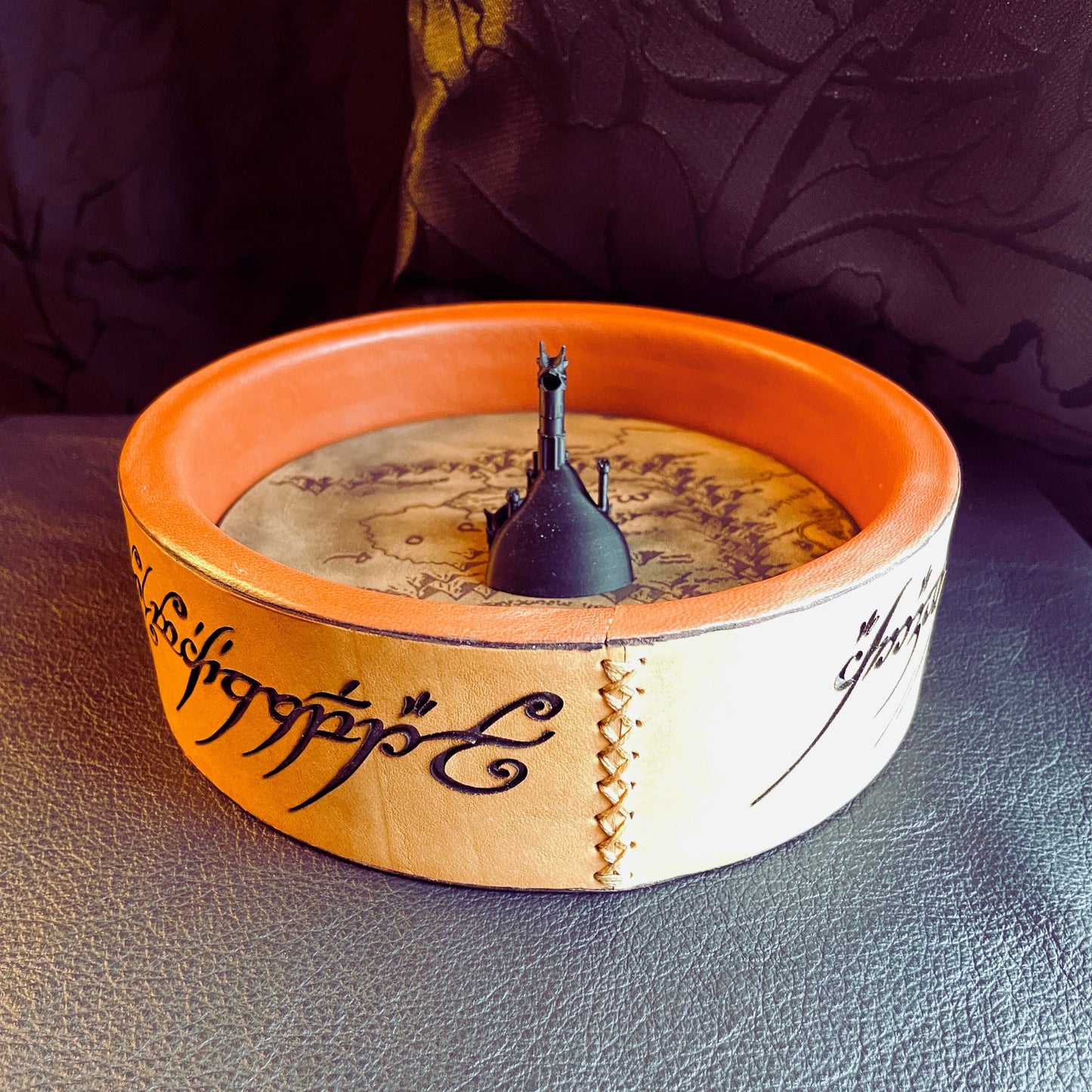 SteamVoyage - vassoio lancia dadi Torre di Sauron in cuoio e legno con incisione a laser della Mappa della Terra di Mezzo e Torre di Sauron in 3d; sul bordo del vassoio lancia dadi è presente l'incisione in elfico sull'Anello del Potere e il fondo nasconde una power bank in grado di illuminare la scritta dell'anello grazie ad un telecomando