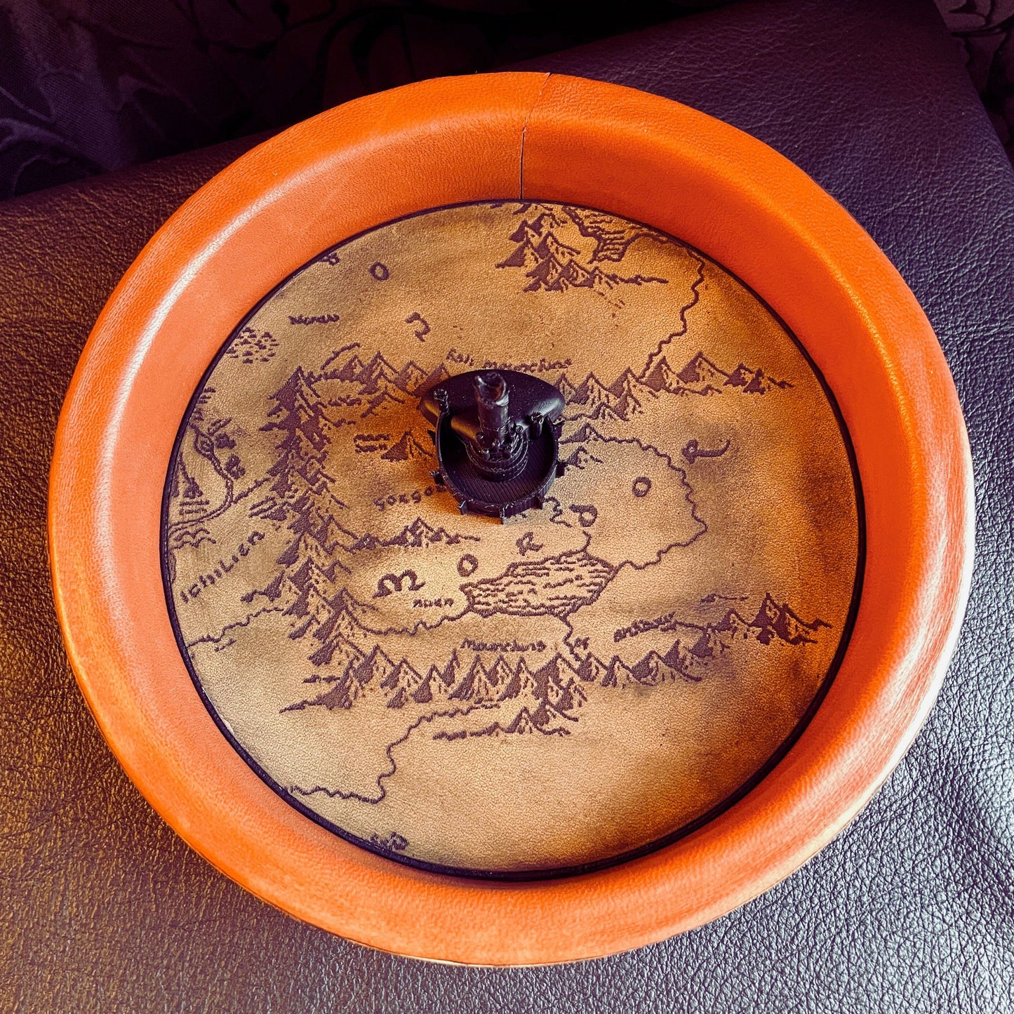 SteamVoyage - vassoio lancia dadi Torre di Sauron in cuoio e legno con incisione a laser della Mappa della Terra di Mezzo e Torre di Sauron in 3d; sul bordo del vassoio lancia dadi è presente l'incisione in elfico sull'Anello del Potere e il fondo nasconde una power bank in grado di illuminare la scritta dell'anello grazie ad un telecomando