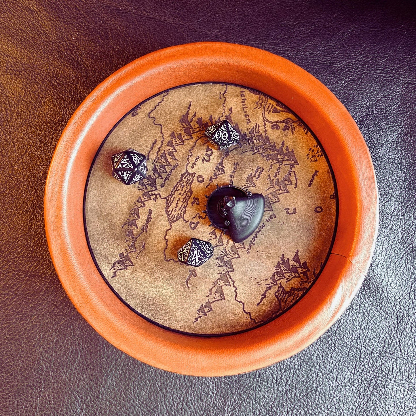 SteamVoyage - vassoio lancia dadi Torre di Sauron in cuoio e legno con incisione a laser della Mappa della Terra di Mezzo e Torre di Sauron in 3d; sul bordo del vassoio lancia dadi è presente l'incisione in elfico sull'Anello del Potere e il fondo nasconde una power bank in grado di illuminare la scritta dell'anello grazie ad un telecomando