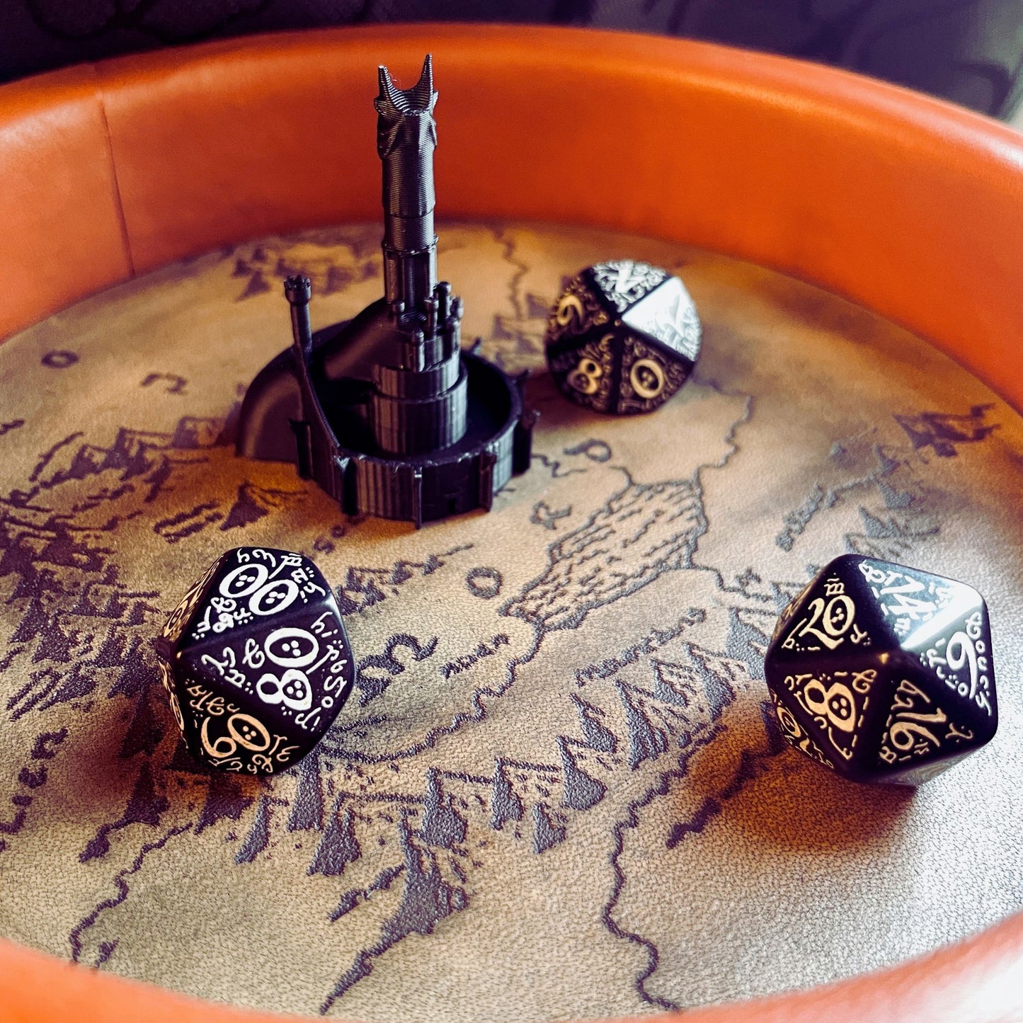 SteamVoyage - vassoio lancia dadi Torre di Sauron in cuoio e legno con incisione a laser della Mappa della Terra di Mezzo e Torre di Sauron in 3d; sul bordo del vassoio lancia dadi è presente l'incisione in elfico sull'Anello del Potere e il fondo nasconde una power bank in grado di illuminare la scritta dell'anello grazie ad un telecomando