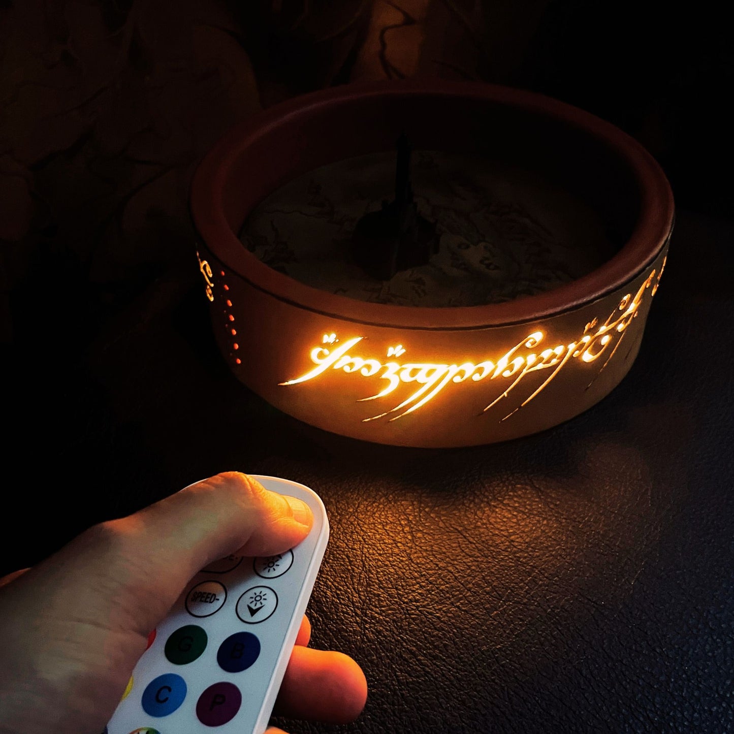 SteamVoyage - vassoio lancia dadi Torre di Sauron in cuoio e legno con incisione a laser della Mappa della Terra di Mezzo e Torre di Sauron in 3d; sul bordo del vassoio lancia dadi è presente l'incisione in elfico sull'Anello del Potere e il fondo nasconde una power bank in grado di illuminare la scritta dell'anello grazie ad un telecomando