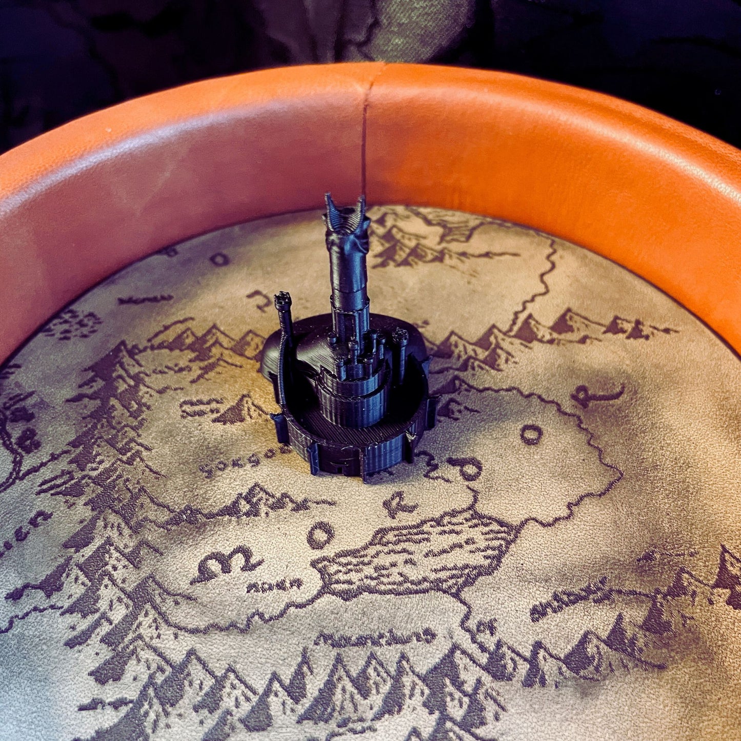 SteamVoyage - vassoio lancia dadi Torre di Sauron in cuoio e legno con incisione a laser della Mappa della Terra di Mezzo e Torre di Sauron in 3d; sul bordo del vassoio lancia dadi è presente l'incisione in elfico sull'Anello del Potere e il fondo nasconde una power bank in grado di illuminare la scritta dell'anello grazie ad un telecomando