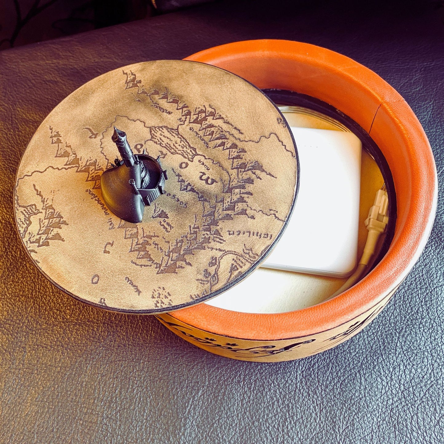 SteamVoyage - vassoio lancia dadi Torre di Sauron in cuoio e legno con incisione a laser della Mappa della Terra di Mezzo e Torre di Sauron in 3d; sul bordo del vassoio lancia dadi è presente l'incisione in elfico sull'Anello del Potere e il fondo nasconde una power bank in grado di illuminare la scritta dell'anello grazie ad un telecomando