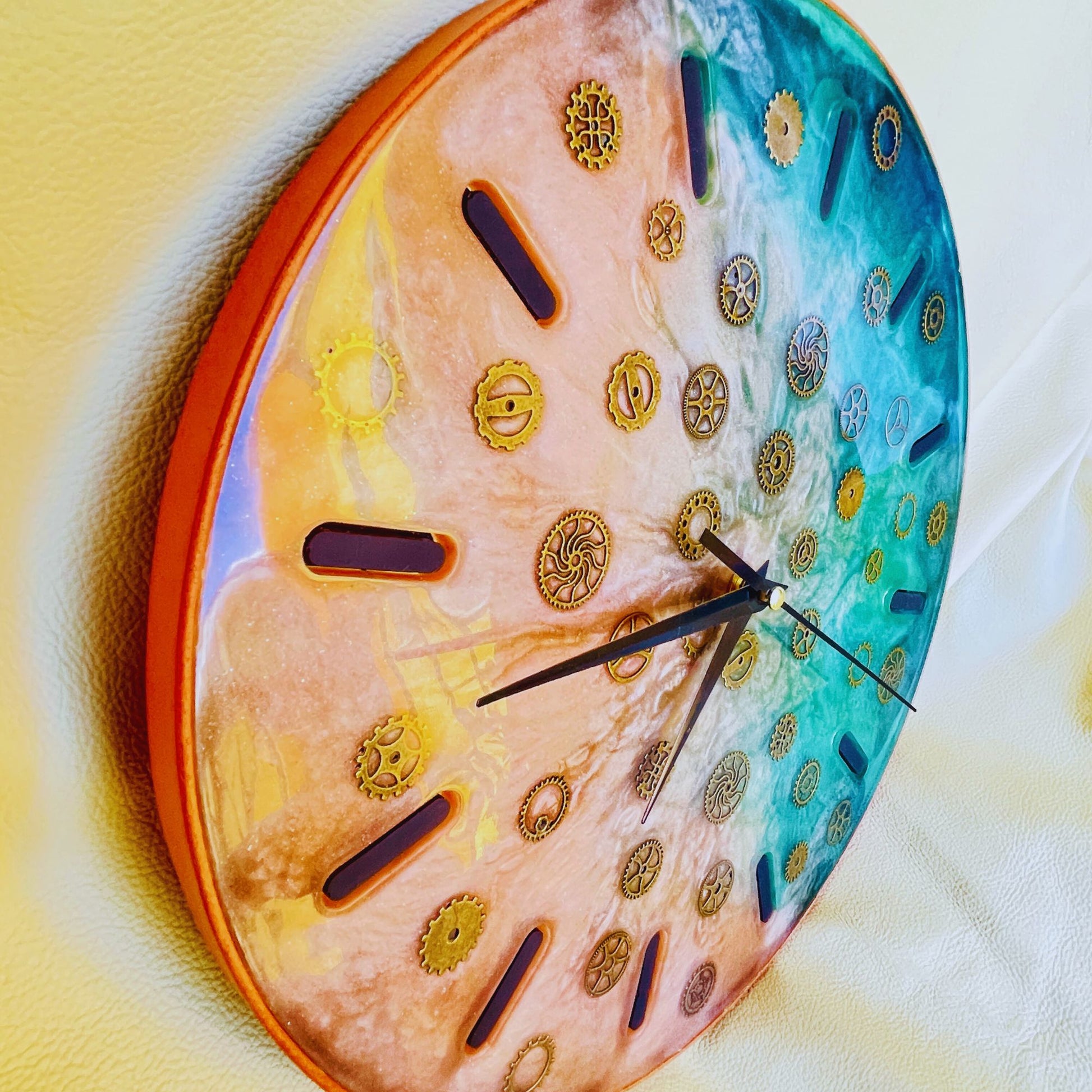 SteamVoyage-Orologio Steampunk da muro a batteria in resina epossidica rosa e verde con inserti di ingranaggi in ferro bronzato e struttura di resina epossidica nera bordata di cuoio conciato al vegetale.