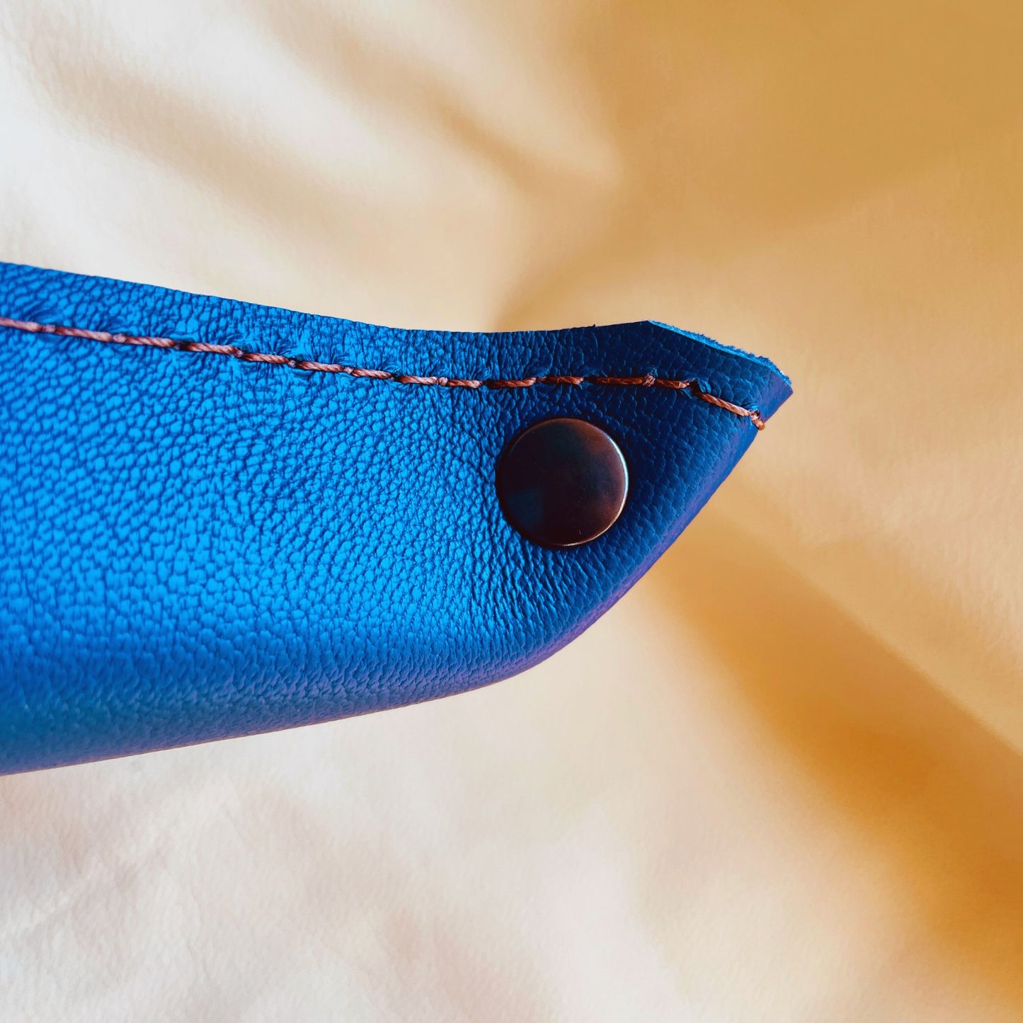 SteamVoyage - vassoio lancia dadi in cuoio dipinto a mano rivestito con pelle blu, dotato di quattro bottoni angolari per la chiusura e cucitura sul bordo. Il vassoio lancia dadi è decorato con l'immagine di un beholder, mostro tipico di Dungeons and dragons, dipinto con colori vivaci: viola e blu