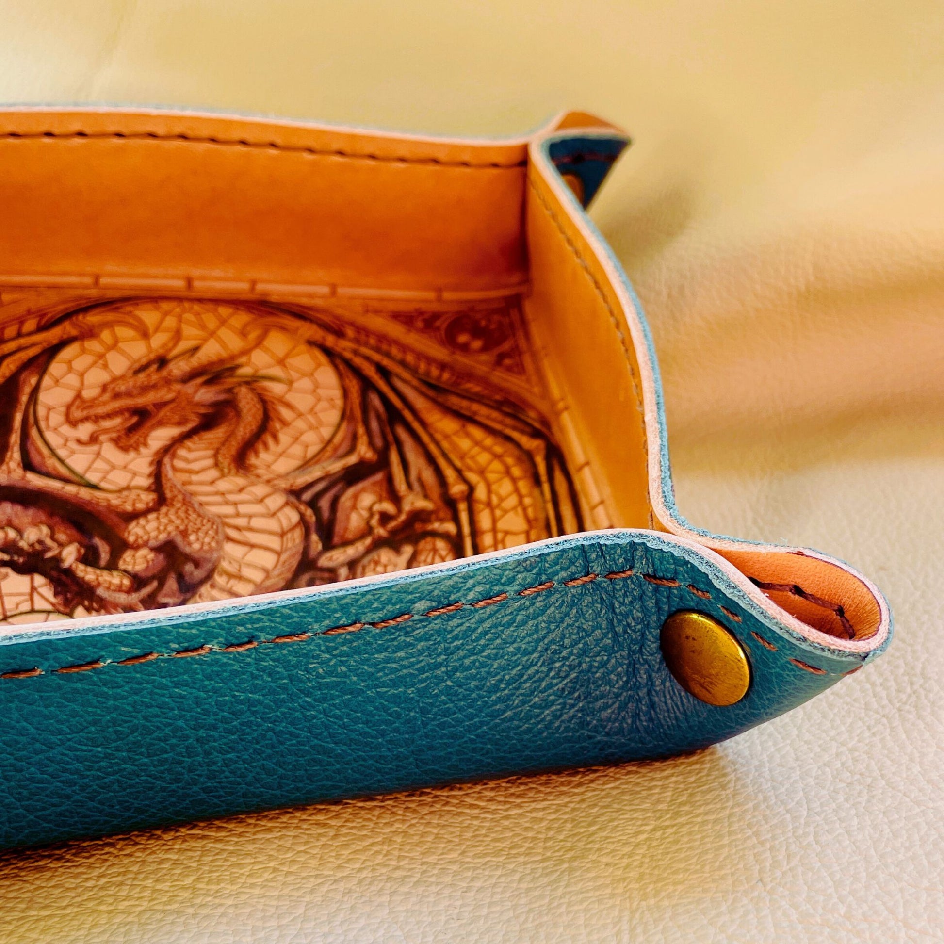 SteamVoyage - vassoio lancia dadi artigianale rivestito in pelle blu con quattro bottoni dorati agli angoli, cucitura sul bordo e incisione laser di un drago dipinto a mano in verde e oro.